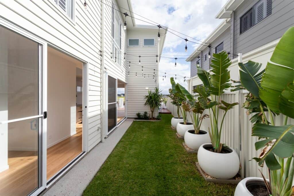 Narrow side garden with palms beside a two-storey home